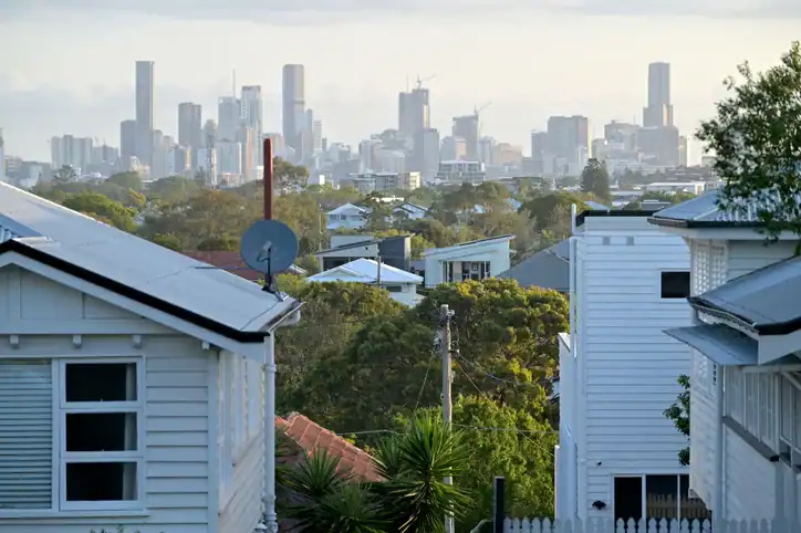 City skyline view from a suburban neighborhood with white houses and greenery.